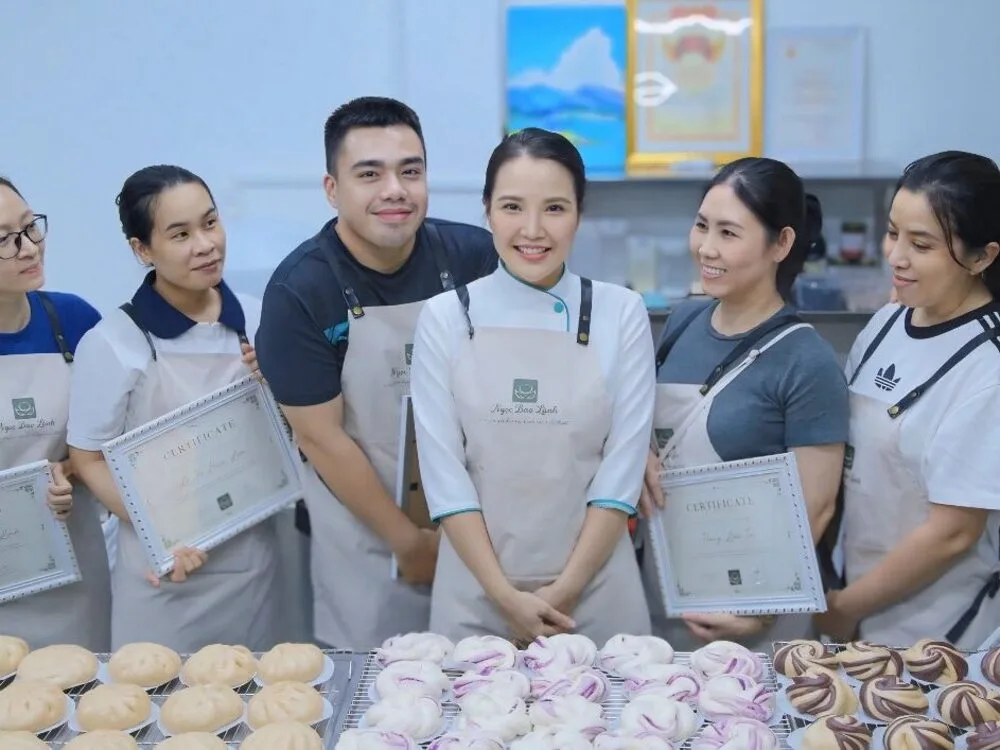 Cô Ngọc cùng học viên tốt nghiệp cầm chứng chỉ bên khay bánh bao
